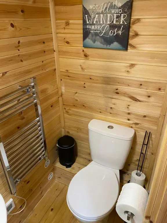 a bathroom with a white toilet in a wooden wall at An Cabar - Cabin in Aviemore, Cairngorms NP in Aviemore