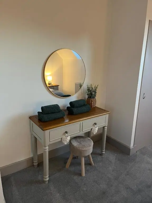 a dressing table with a mirror and a stool at Willow's Cottage in Auldearn
