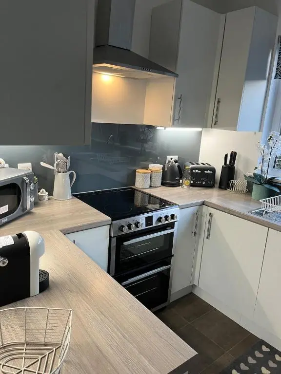 a kitchen with white cabinets and a stove top oven at Willow's Cottage in Auldearn