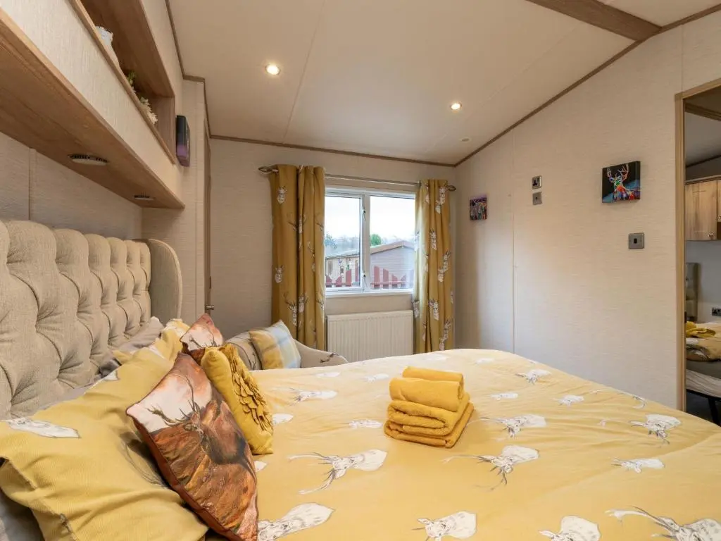 a bedroom with a large bed with yellow sheets at Chalet Cairn View by Interhome in Aviemore