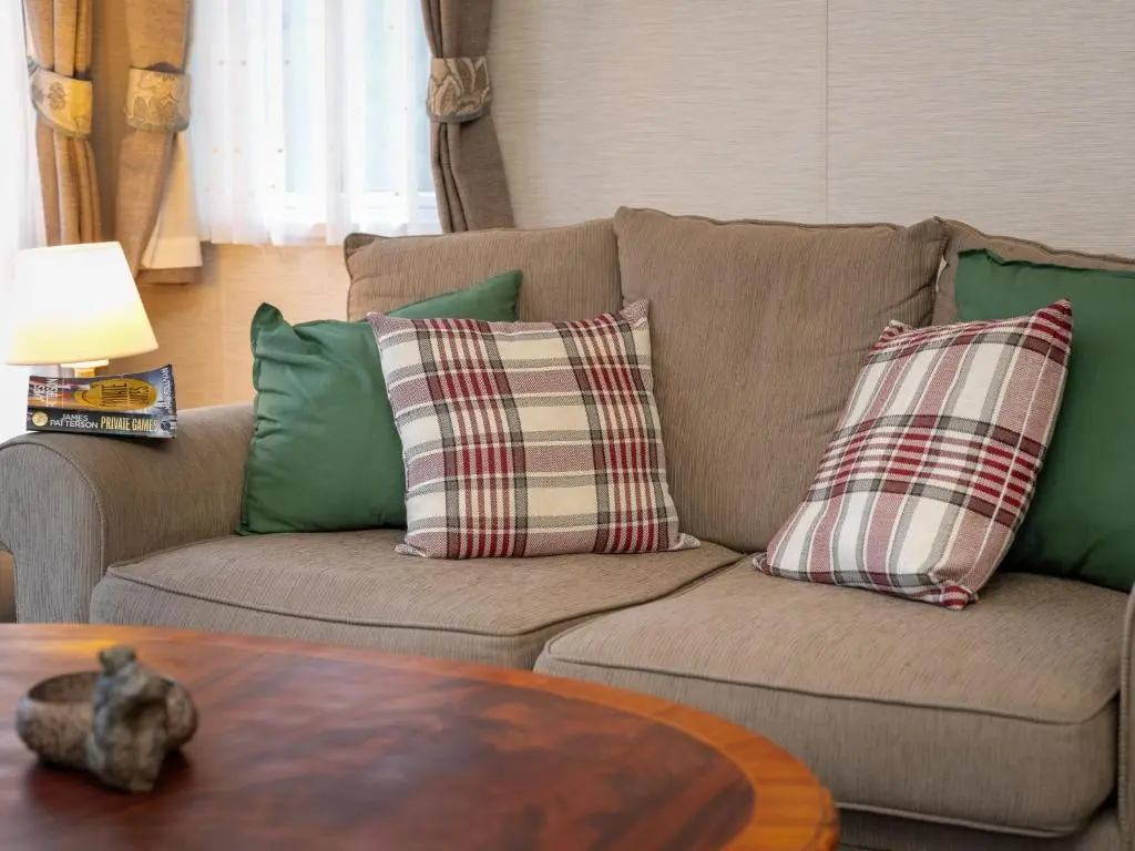 a living room with a couch with pillows and a table at Chalet Cairn View by Interhome in Aviemore