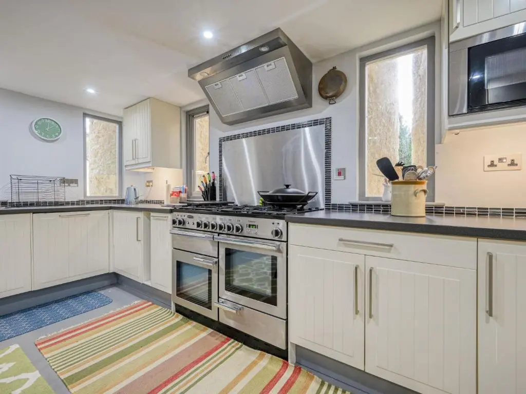a kitchen with white cabinets and a stove top oven at Holiday Home Loch Ness Granary by Interhome in Invermoriston