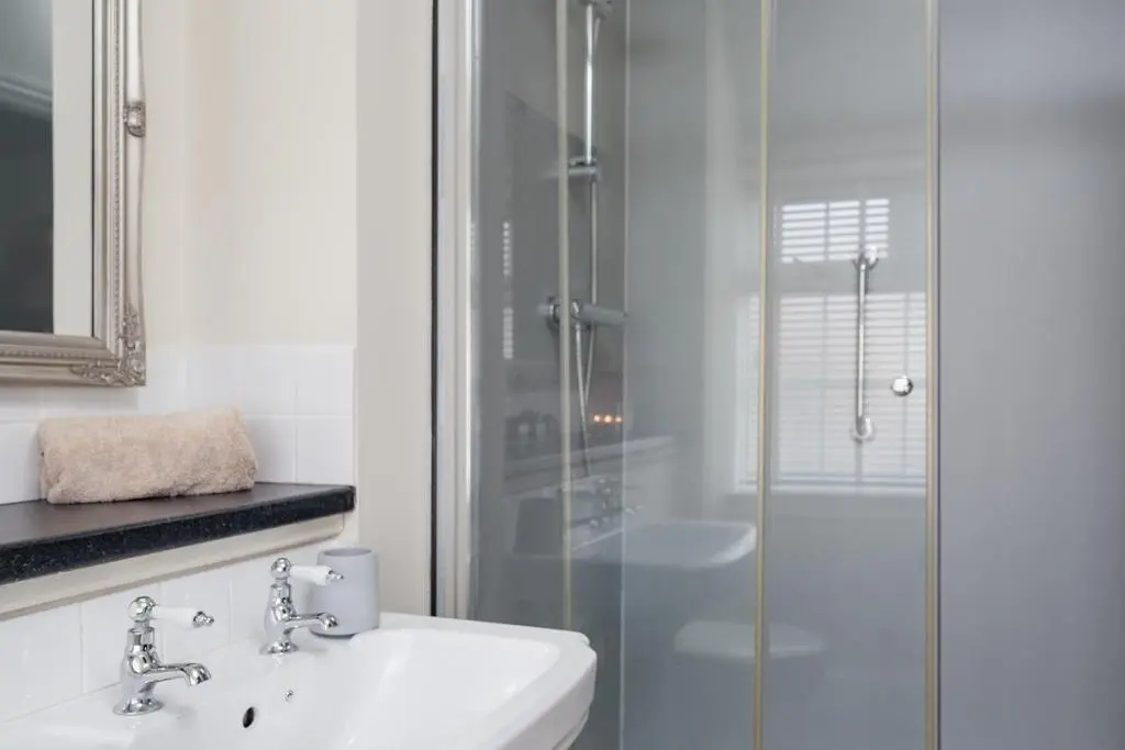 a white bathroom with a sink and a shower at The Old Smithy - Seasgair Lodges in Nethy Bridge