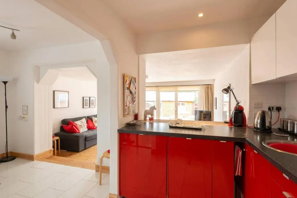 a kitchen with red cabinets and a living room at 4guests-2br-privategarden-freeparking in Aviemore