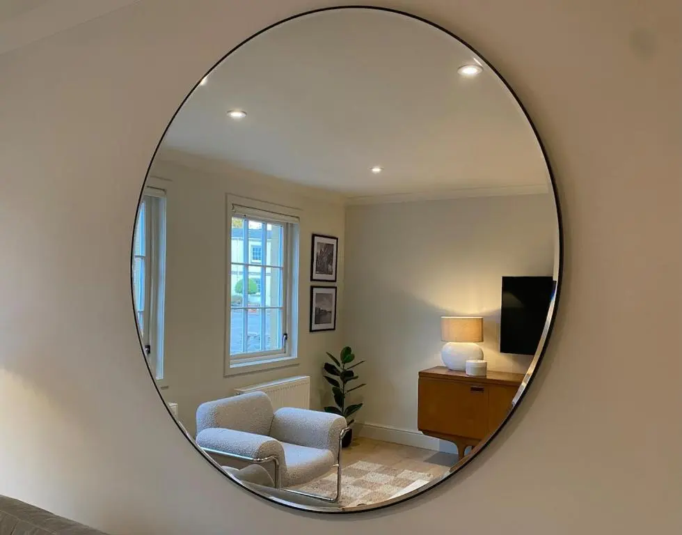 a mirror reflecting a living room with a chair and a television at Warm, stylish 2-bed in Crown, Inverness in Inverness