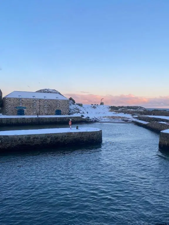 a person standing on the shore of a body of water at Number Forty Two, Portsoy - A 3 bedroom cottage with sea views in Portsoy