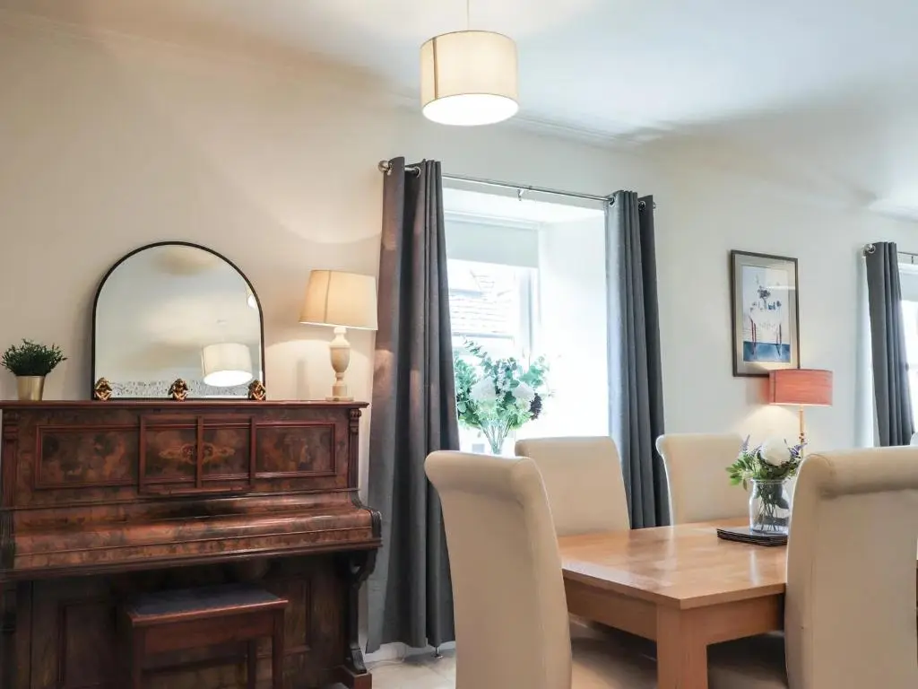 a dining room with a wooden table and a mirror at Mary Ann Villa in Inverness