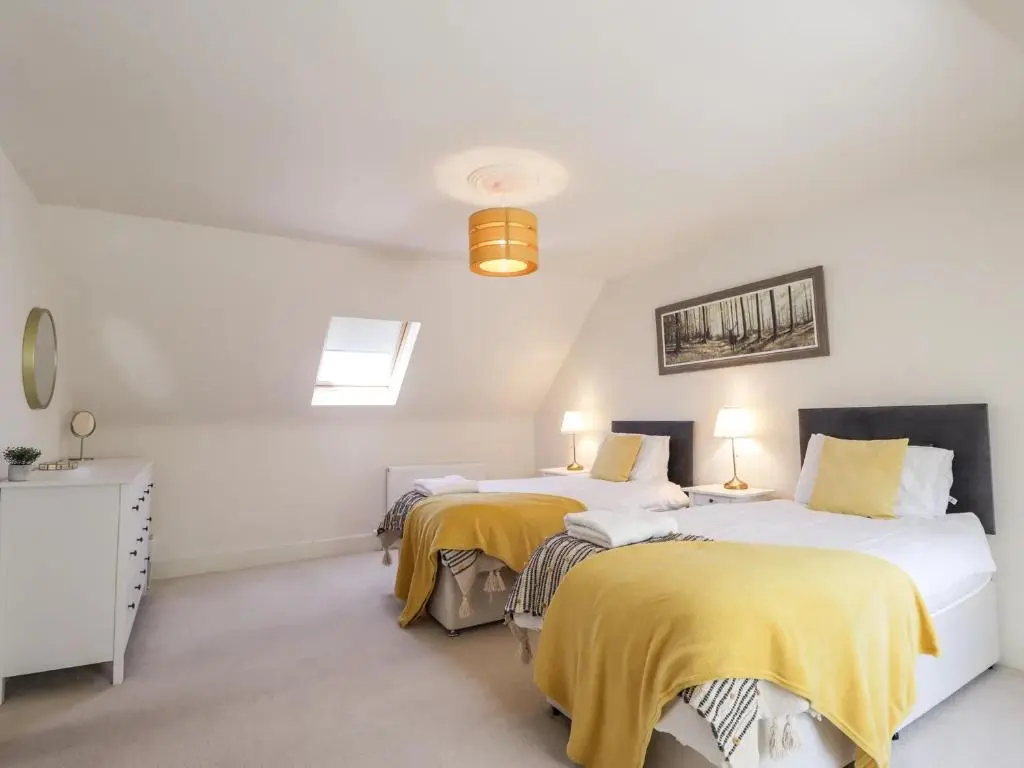 two beds in a white room with yellow sheets at Mary Ann Villa in Inverness