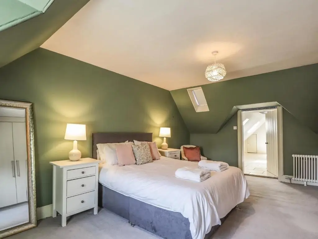 a bedroom with a large bed and a green wall at Mary Ann Villa in Inverness