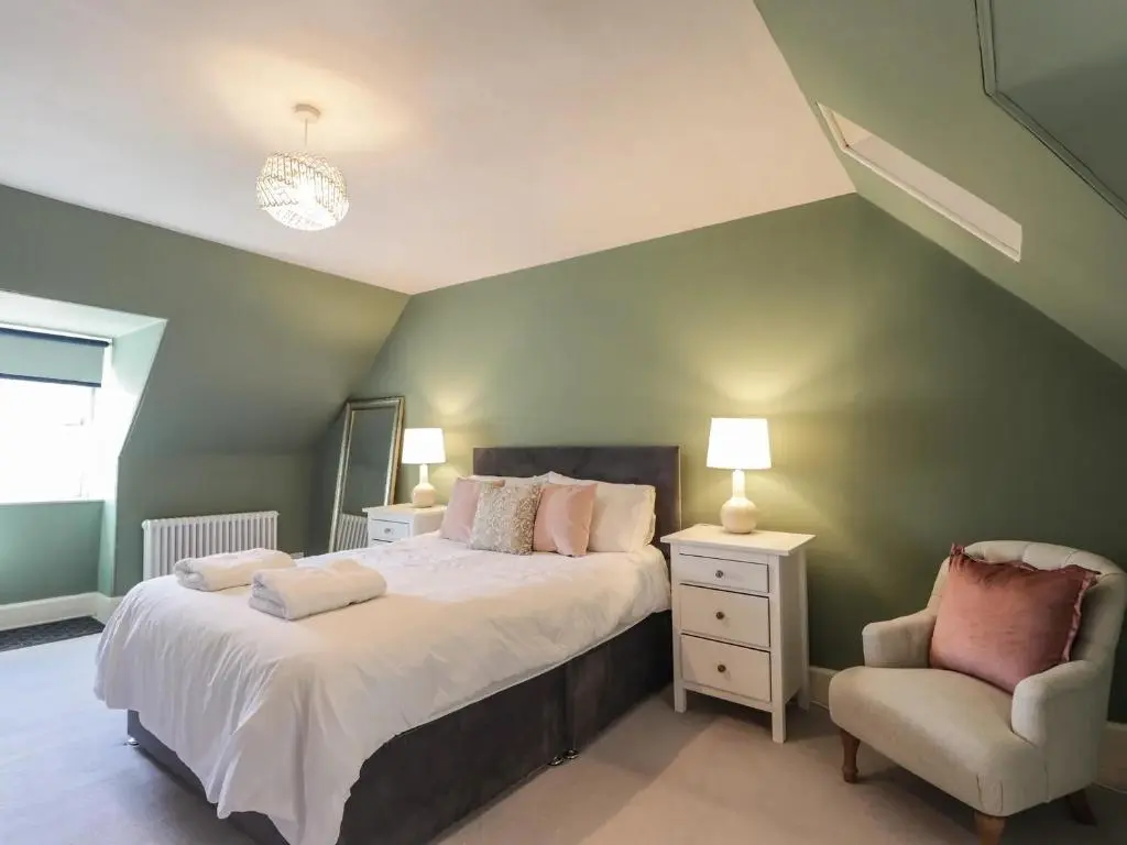 a bedroom with a large bed and a chair at Mary Ann Villa in Inverness