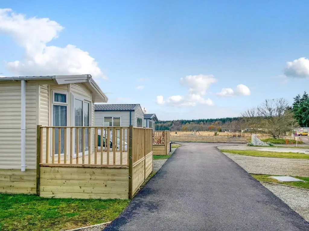 a house with a wooden deck next to a driveway at The Kestrel - Ukc6920 in Forres