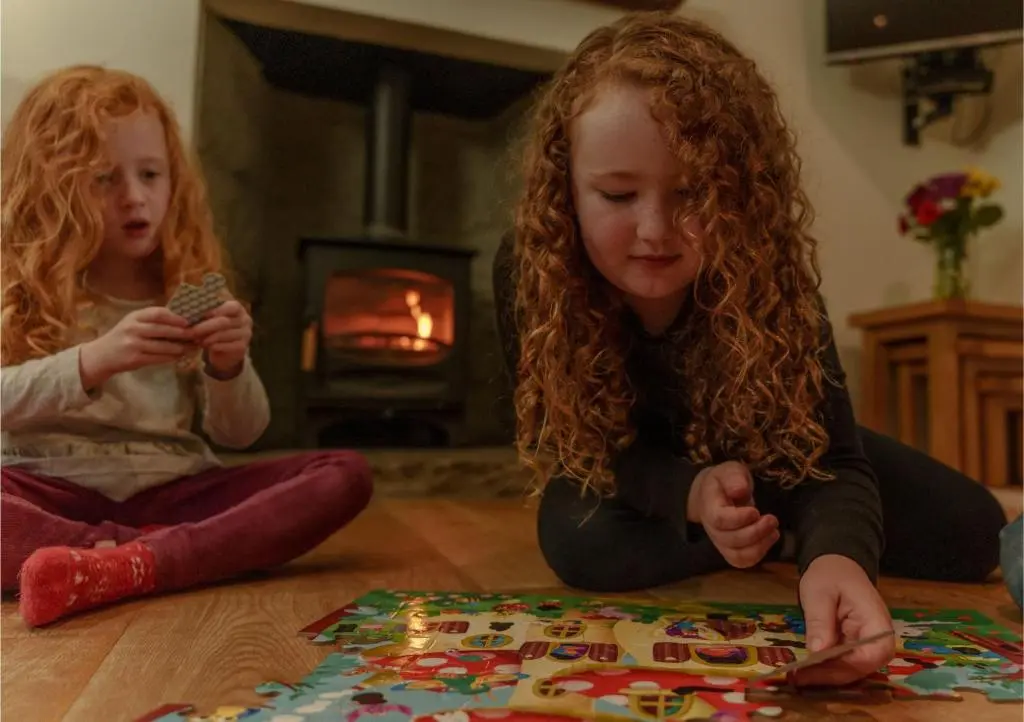 two young girls playing with a puzzle on the floor at Sherrabeg Cottage in Laggan