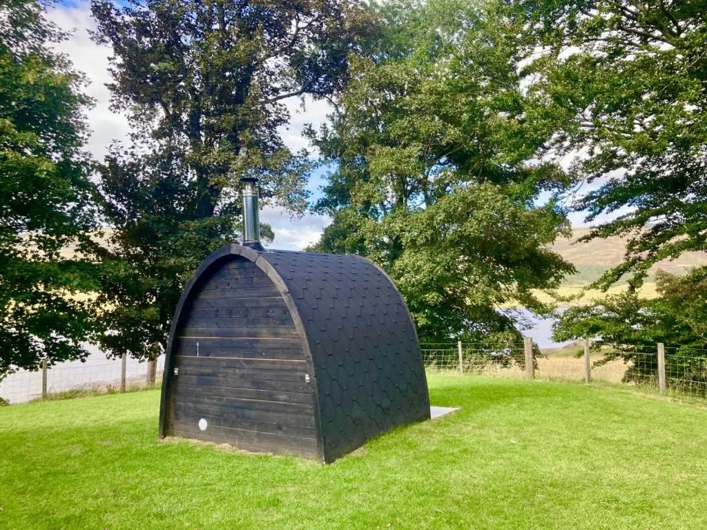 a small structure in the grass in a field at Sherrabeg Cottage in Laggan