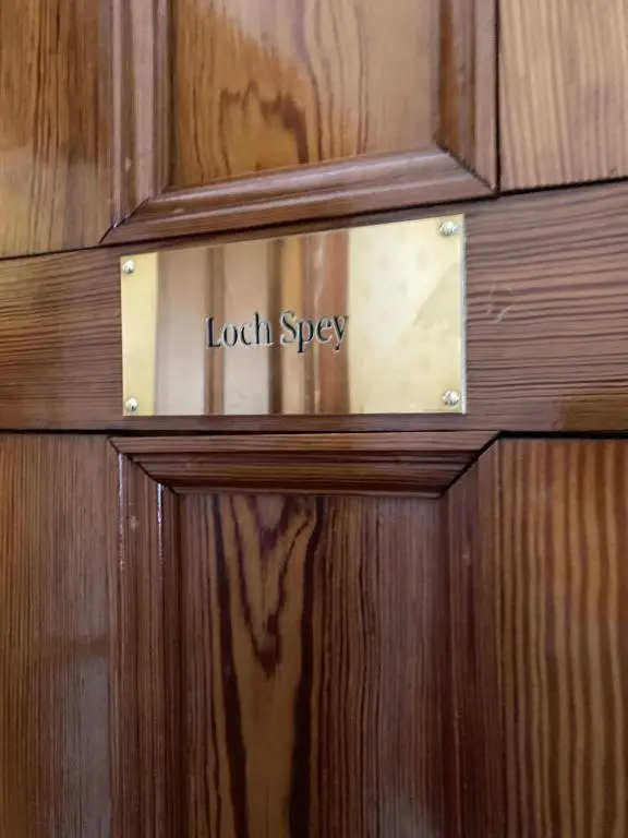 a wooden door with a sign that reads local spy at Sherramore Lodge in Laggan
