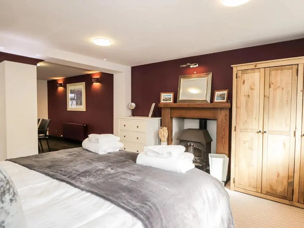 a bedroom with a large bed and a fireplace at Mary Ann Apartment in Inverness