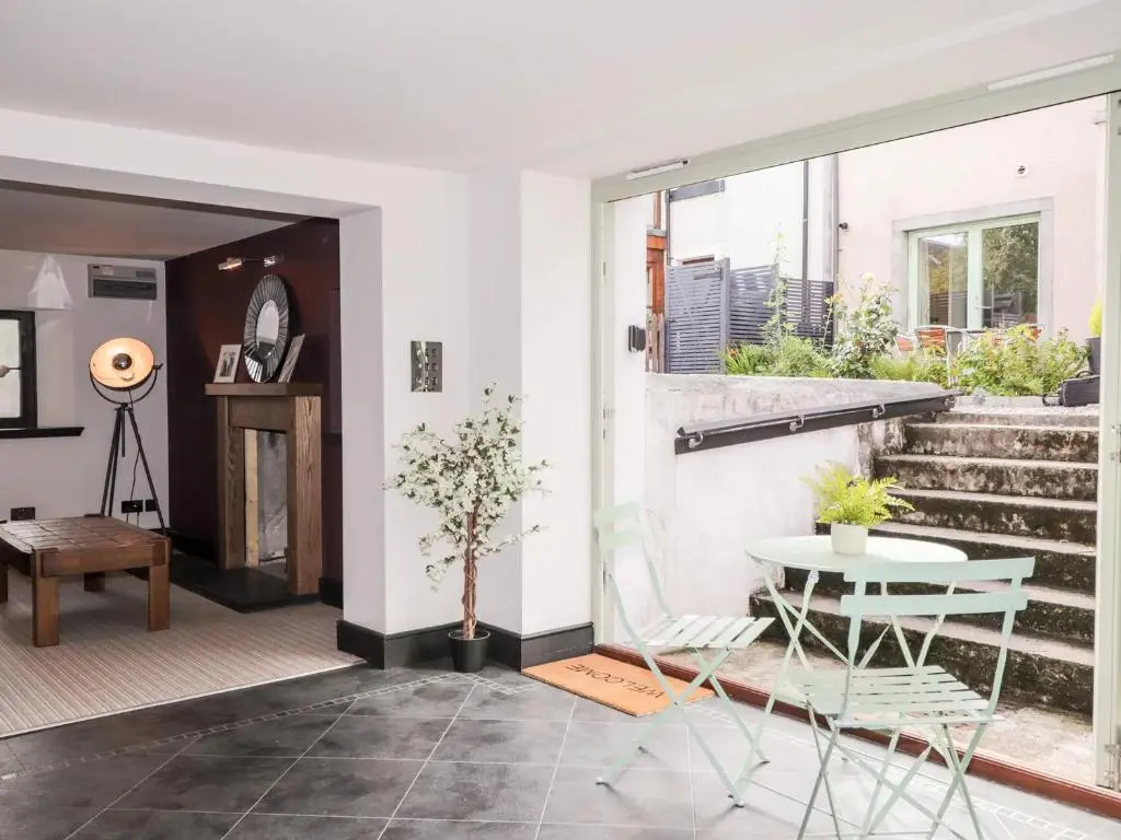 a living room with a table and chairs and stairs at Mary Ann Apartment in Inverness