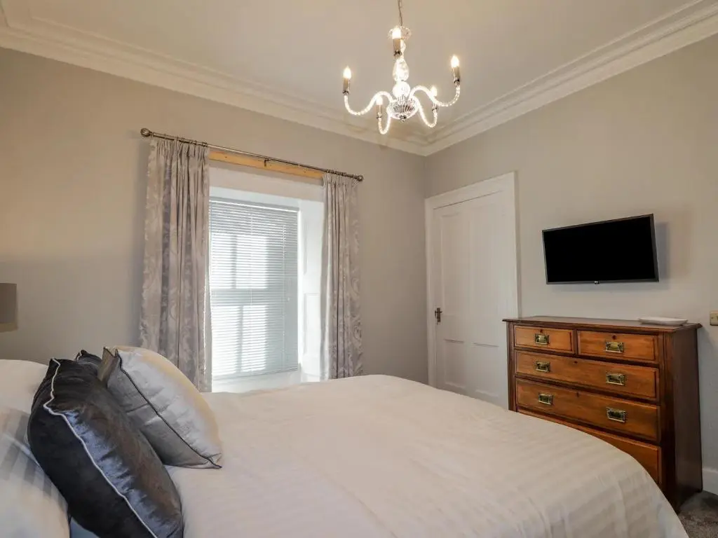 a bedroom with a bed and a television and a chandelier at Porter's Lodge in Inverness
