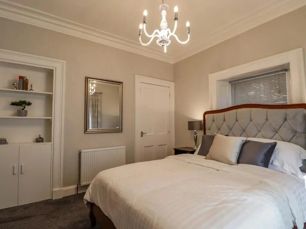 a bedroom with a large bed and a chandelier at Porter's Lodge in Inverness