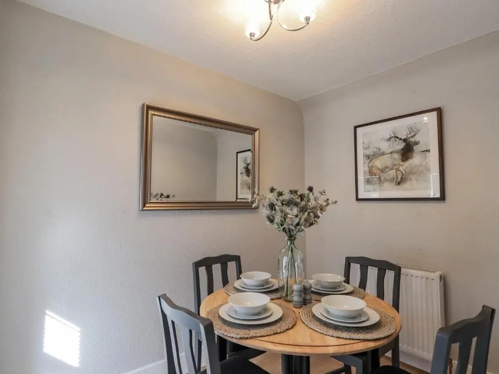 a dining room with a table with chairs and a mirror at Porter's Lodge in Inverness