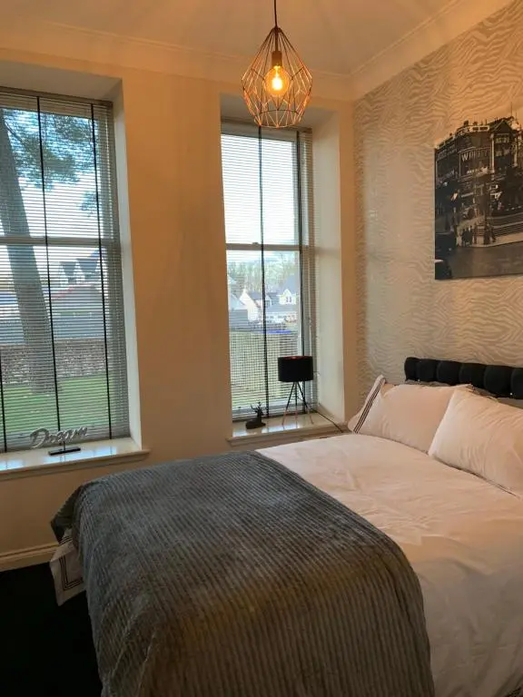 a bedroom with a bed with windows and a chandelier at Junique Modern Ground Floor Apartment - 2 bedrooms in Aberdeen