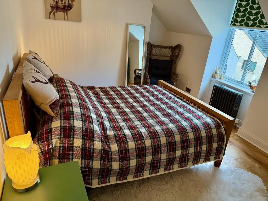 a bedroom with a bed with a plaid blanket at Rosebery House with private garden in quiet area of city centre in Inverness