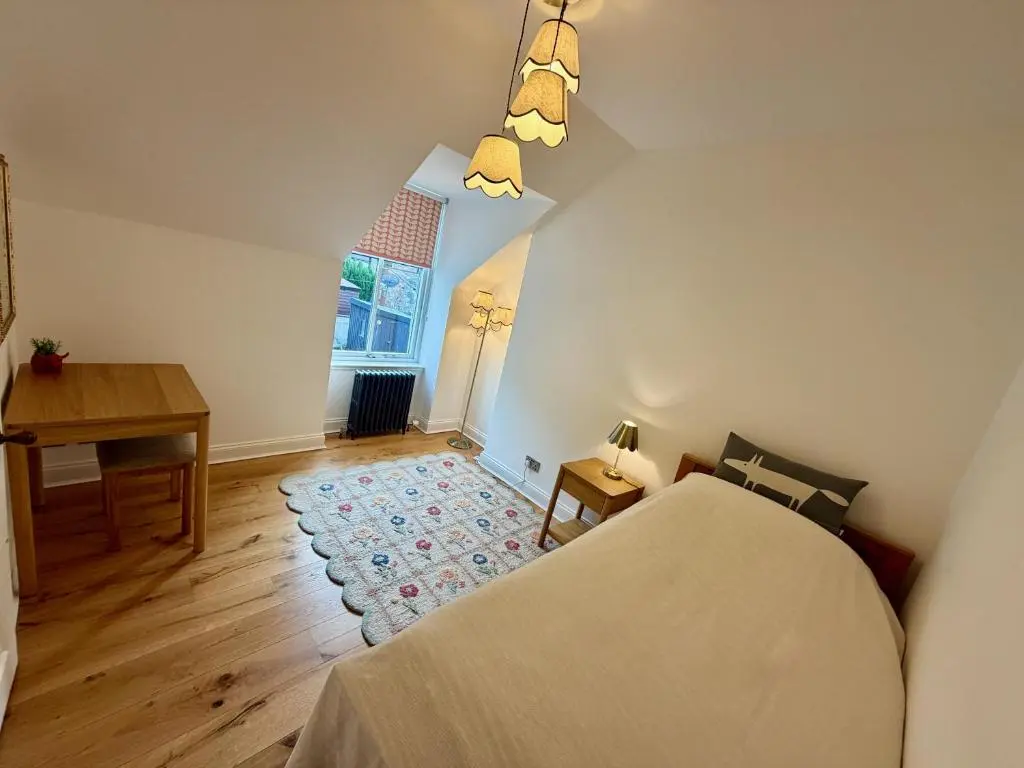 a bedroom with a bed and a desk and a window at Rosebery House with private garden in quiet area of city centre in Inverness