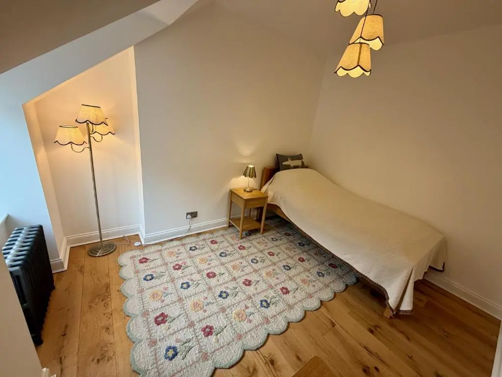 a bedroom with a bed and a lamp and a rug at Rosebery House with private garden in quiet area of city centre in Inverness