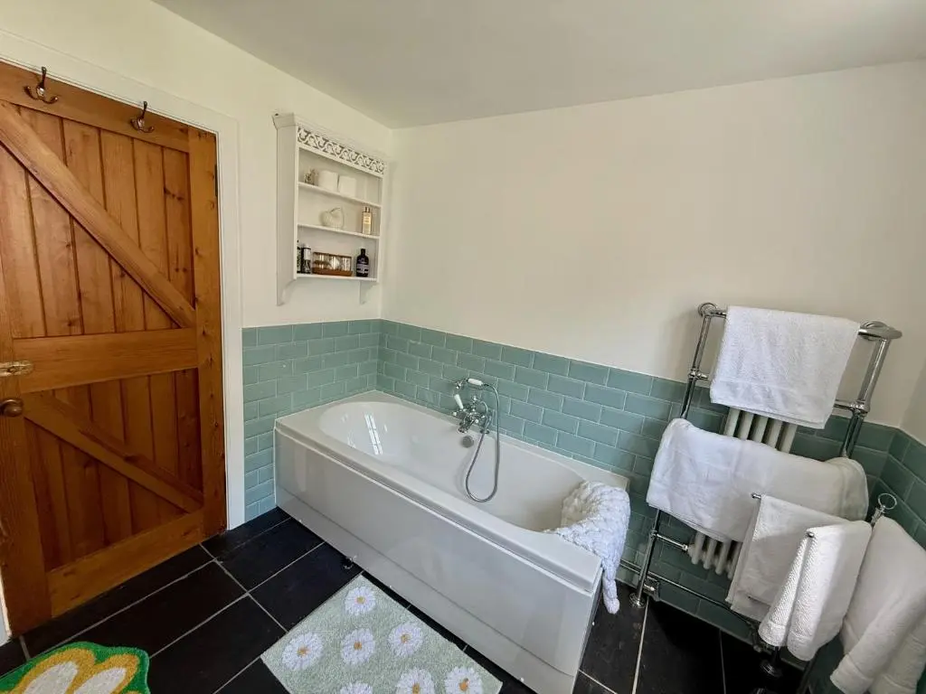 a bathroom with a white tub and blue tiles at Rosebery House with private garden in quiet area of city centre in Inverness