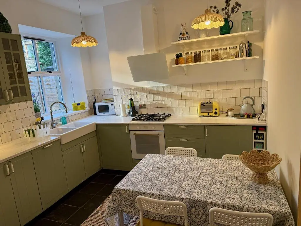 a kitchen with a table and a sink and a stove at Rosebery House with private garden in quiet area of city centre in Inverness