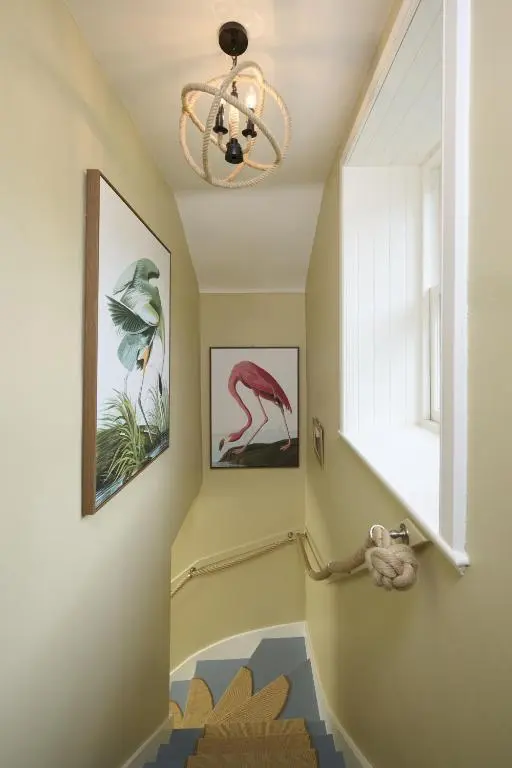 a hallway with a staircase with a chandelier at Garden Cottage in Inverness