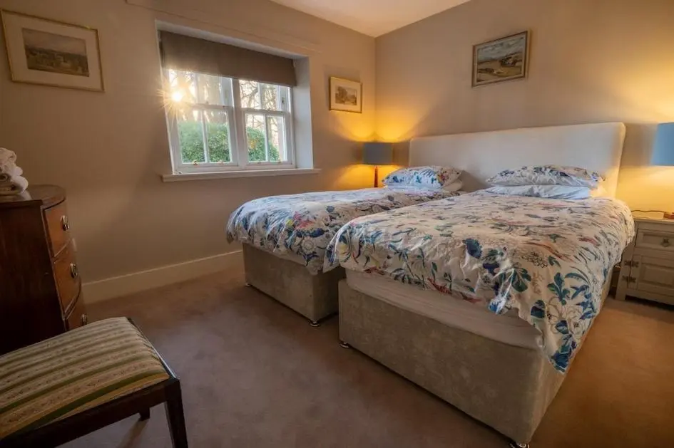 a bedroom with two beds and a window at Foulis Castle Gate Lodge in Evanton