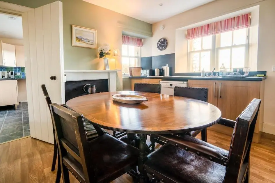 a kitchen with a wooden table and chairs in a room at Foulis Castle Gate Lodge in Evanton
