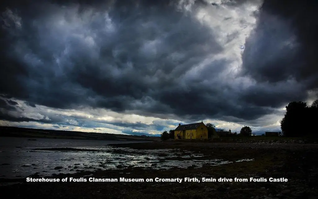 a house on a beach under a cloudy sky at Foulis Castle Gate Lodge in Evanton