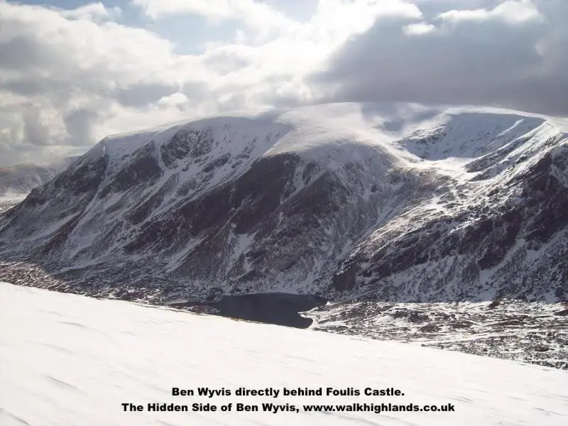 a snow covered mountain with a lake in front of it at Foulis Castle Gate Lodge in Evanton