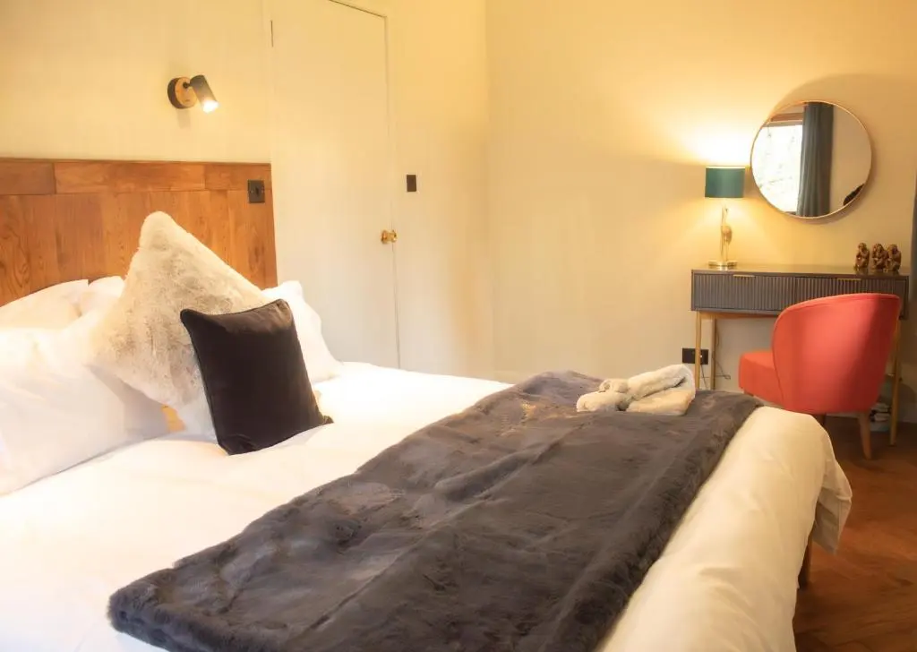 a bedroom with a large bed and a red chair at Telford Cottage in Kincraig