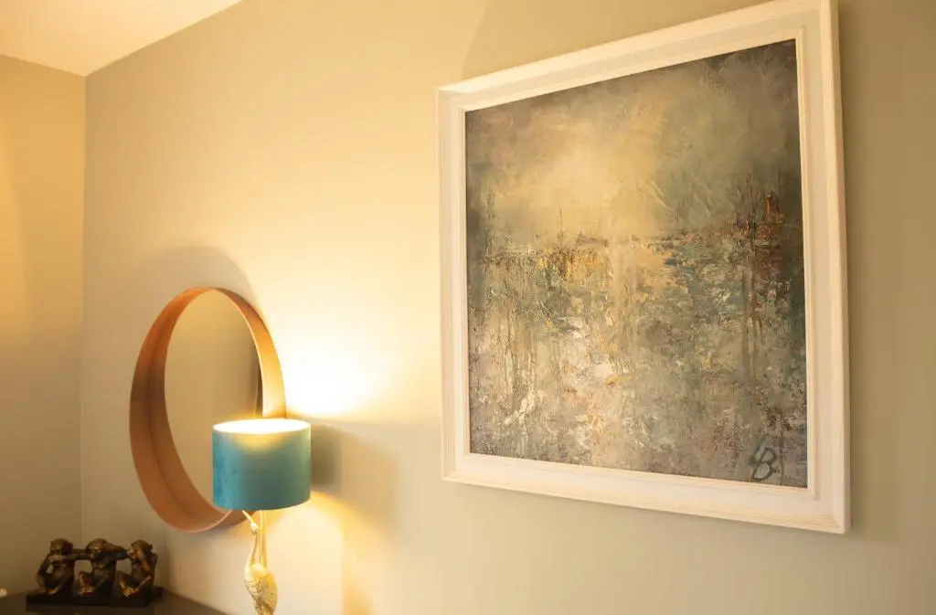 a painting on a wall with a lamp and a light at Fraser Cottage in Kincraig