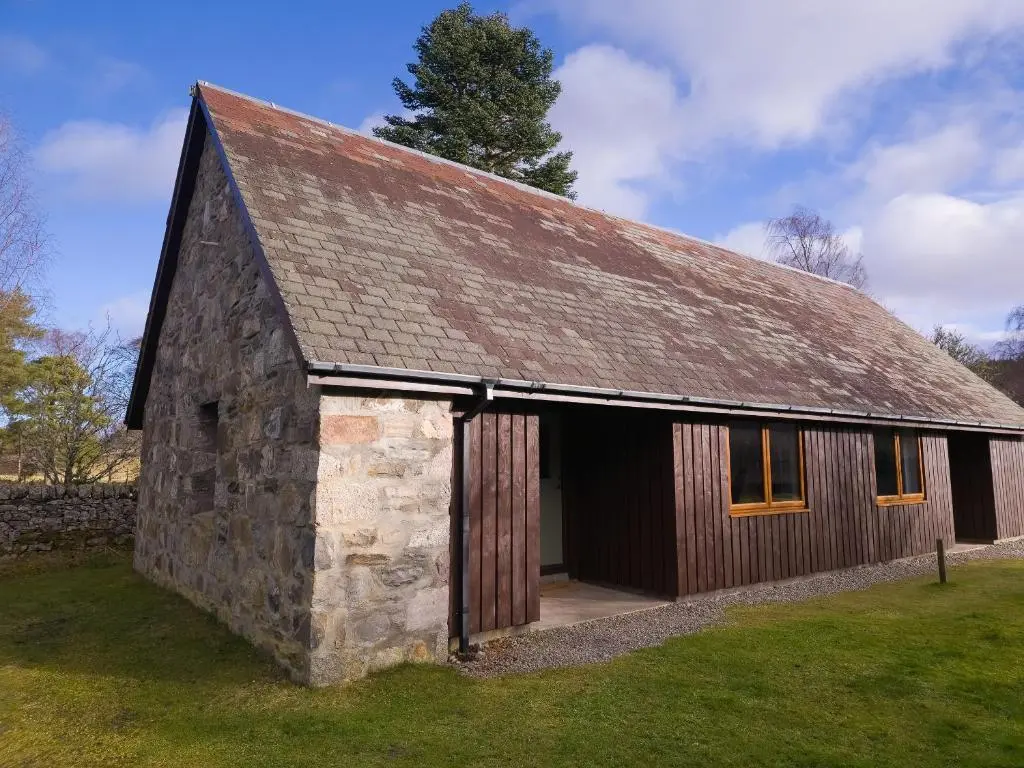 an old stone barn with its door open at Fraser Cottage in Kincraig