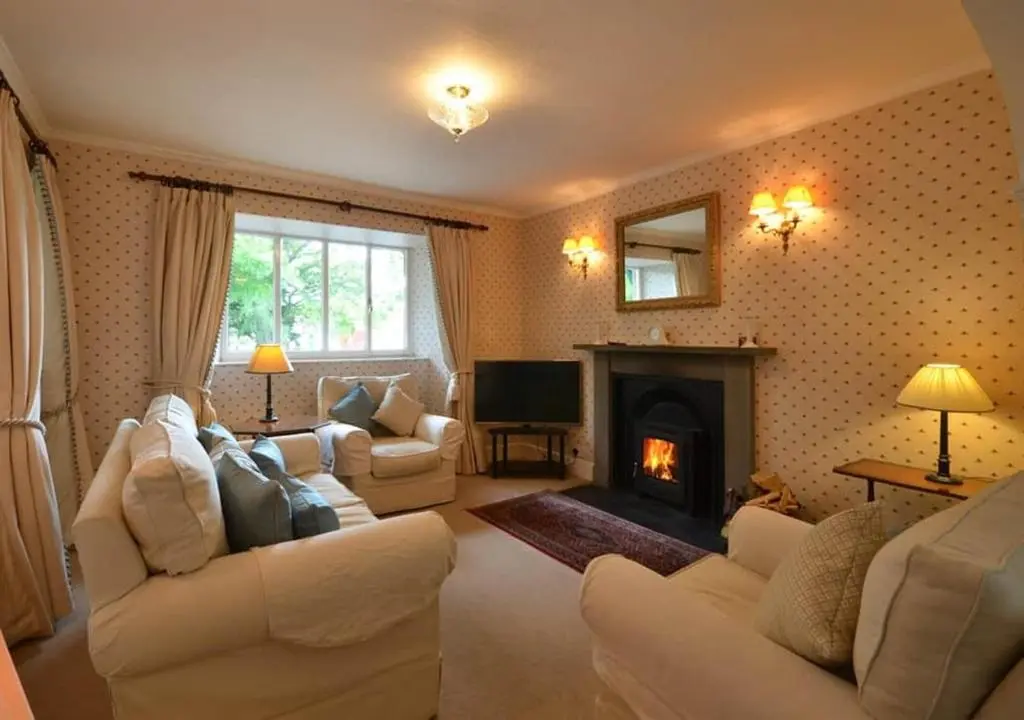 a living room with white furniture and a fireplace at Swiss Cottage in Ballindalloch
