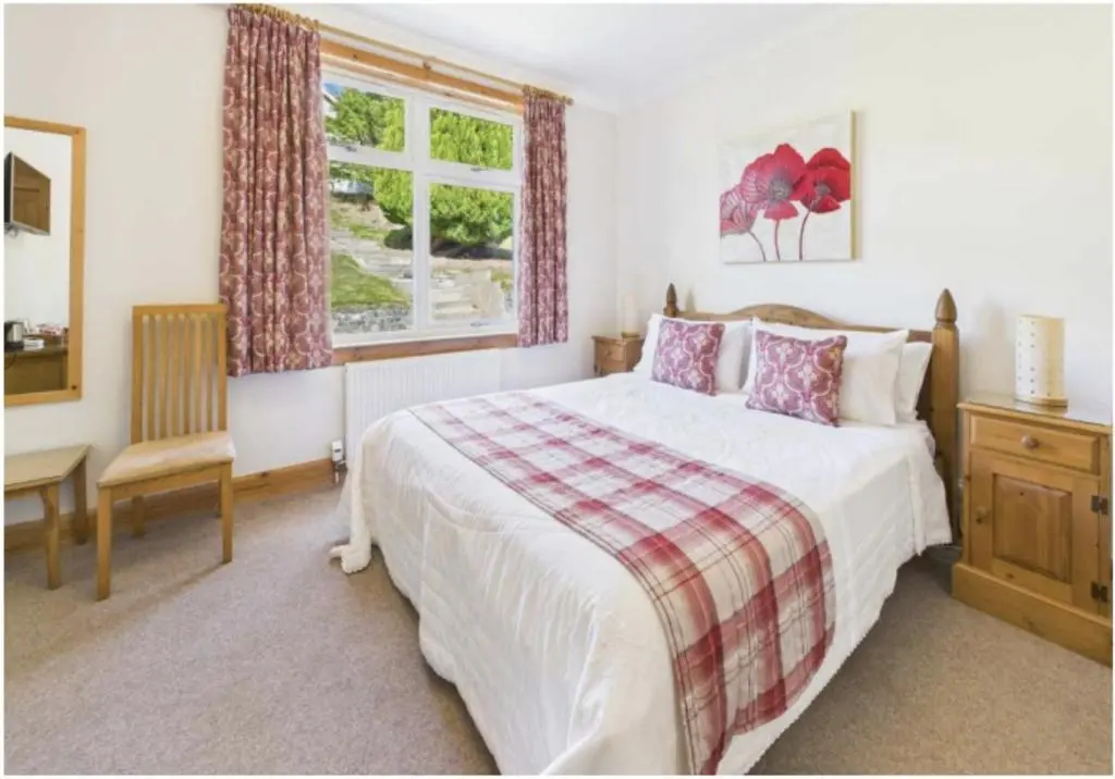 a bedroom with a bed and a desk and a window at Strathview Lodge B&B in Dornoch