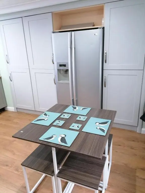 a table in a kitchen with a refrigerator at Hytheview Cottage Whitehills in Whitehills