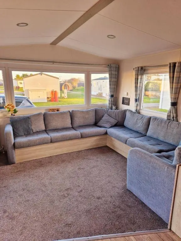 a living room with a blue couch and windows at Badgers Den Silversands in Lossiemouth