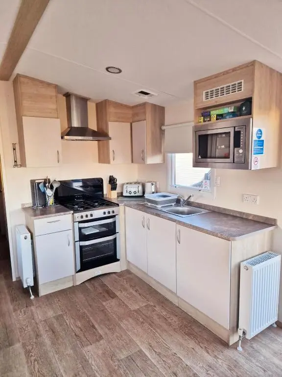 a kitchen with white cabinets and a stove top oven at Badgers Den Silversands in Lossiemouth
