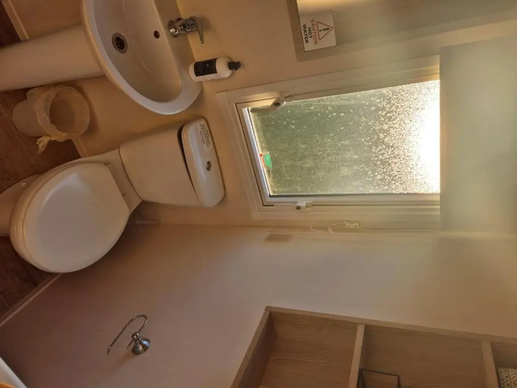 a small bathroom with a toilet and a window at Badgers Den Silversands in Lossiemouth