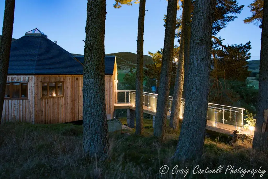 a log cabin in the woods at night at Dalnoid Cottages & Treehouses Nr Glenshee in Glenshee