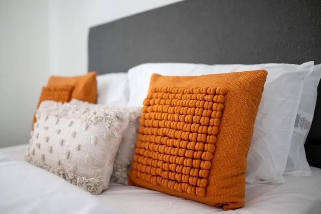 two orange pillows sitting on top of a bed at Charming City Centre Flat in Inverness