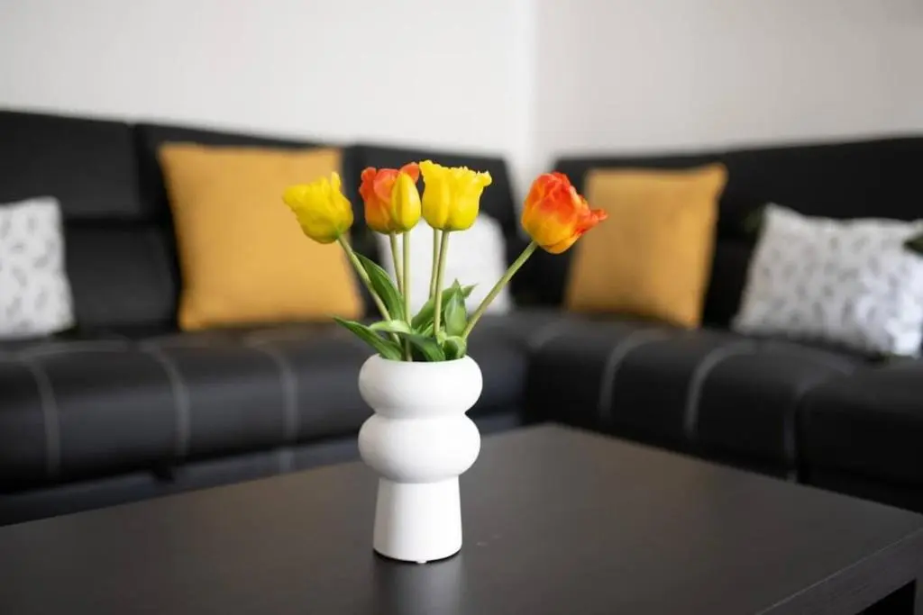 a white vase filled with colorful flowers on a table at Charming City Centre Flat in Inverness