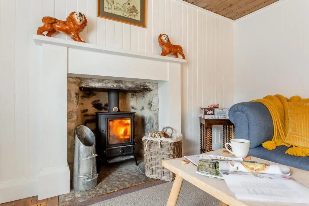 a living room with a fireplace and a blue couch at 2 Bed in Ardgay oc-w30780 in Achnahanat