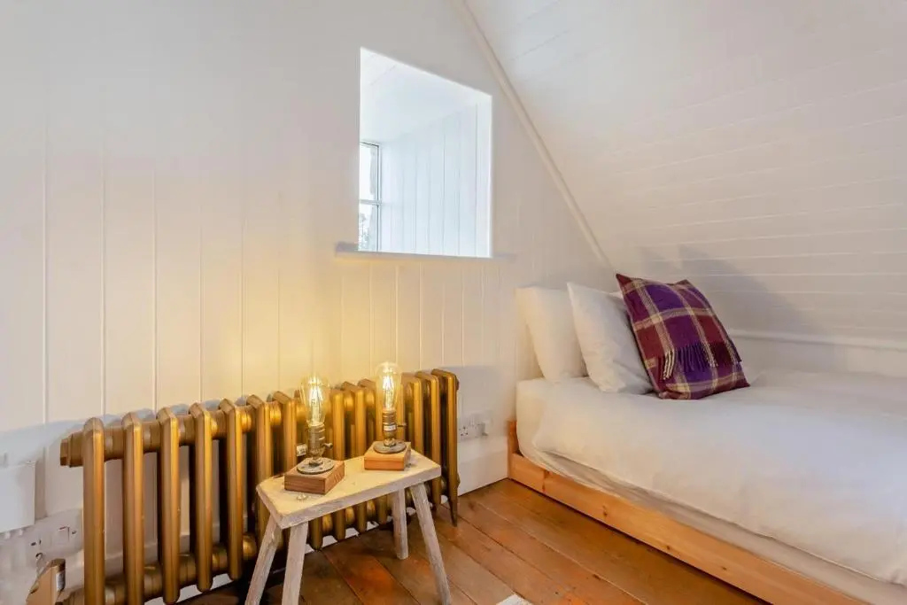 a small attic room with a bed and a radiator at 2 Bed in Ardgay oc-w30780 in Achnahanat