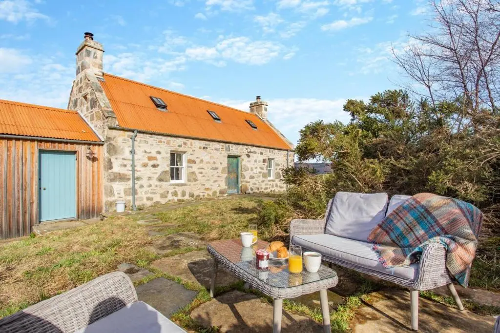 a chair and a table in front of a building at 2 Bed in Ardgay oc-w30780 in Achnahanat