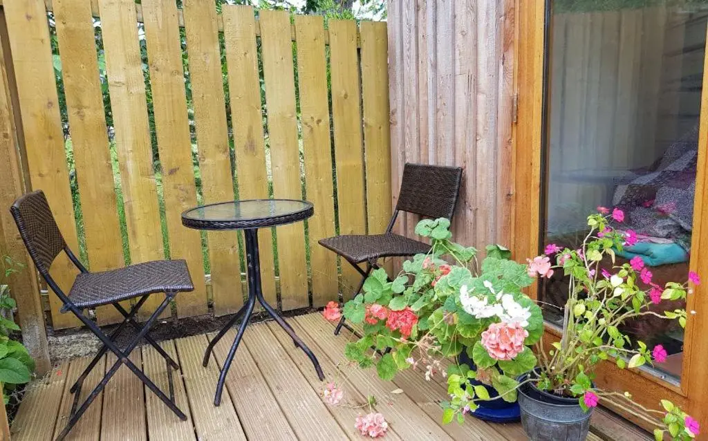 a patio with two chairs and a table and some flowers at Den of Allachlade in Aboyne